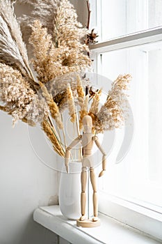 Dry reeds in ceramic vase on windowsill, vintage home interior