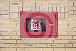 Dry riser inlet box red on brick wall for emergency fire services water connection for hose brigade engine at shopping mall retail