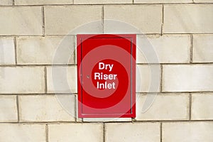 Dry riser inlet box red on brick wall for emergency fire services water connection for hose brigade engine at shopping mall retail