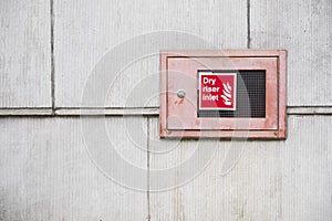 Dry riser inlet box red on brick wall for emergency fire services water connection for hose brigade engine at shopping mall retail