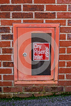 A dry riser inlet cupboard in a brick wall