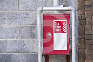 Dry riser red inlet box and sign at wall