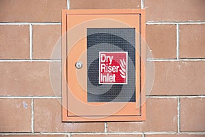 Dry riser red inlet box and sign at wall