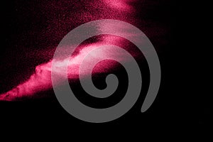 Dry river sand explosion. Pink colored sand splash against black background