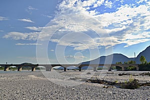 Dry riverbed with bridge, blue sky and clouds in background