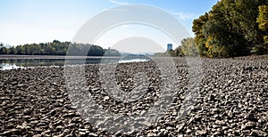 Dry riverbed with stones, visible chimney of a nuclear power plant.