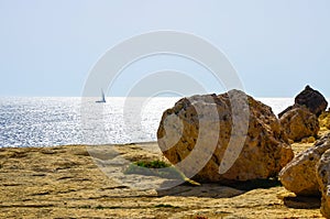 Dry rocky beach and a sailboat on the Mediterranean Sea