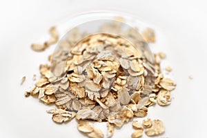 Dry rolled oat flakes oatmeal on white plate
