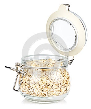 Dry rolled oats in a open transparent glass jar with rubber seal and metal clamp on lid isolated on white background