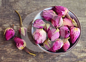 Dry rose buds flowers in a bowl on old wooden table.Healthy herbal drinks concept.Asian ingredient for aromatherapy tea.