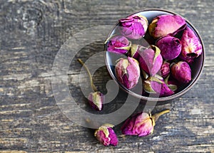 Dry rose buds flowers in a bowl on old wooden table.Healthy herbal drinks concept.Asian ingredient for aromatherapy tea.