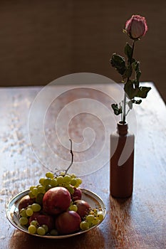 Dry rose flower next to a dish on the table, still life