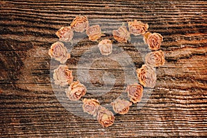 Dry rose flowers heart on wood panel