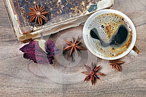 Dry rose in an old vintage book and cup of coffee on a wooden table close up. copy spaces. top view