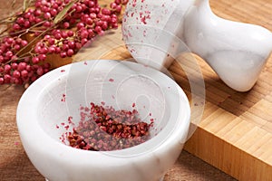 Dry rose pepper in white marble mortar next pestle