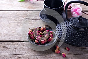 Dry rose tea in bowl and traditional asian tea set on aged woo