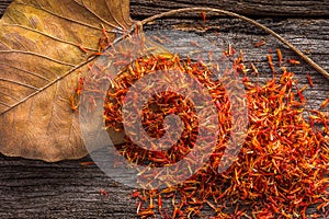 Dry Safflower with leaf on grunge wooden background.