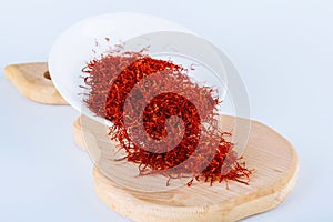 Dry Saffron Spice on Plate on white Background. Wooden board. The use of saffron in cooking, medicine, cosmetology photo