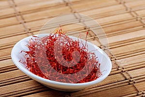 Dry Saffron Spice on a white Plate on Wooden Background photo