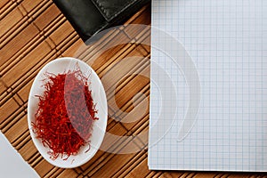Dry Saffron Spice on a white Plate on Wooden Background. Copy space photo