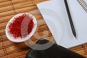 Dry Saffron Spice on a white Plate on Wooden Background with copybook. Copy space photo