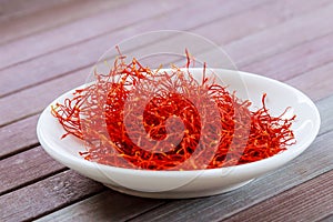 Dry Saffron Spice on a white Plate on Wooden Background photo