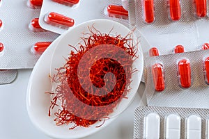 Dry saffron threads and pills in blister on a white background photo