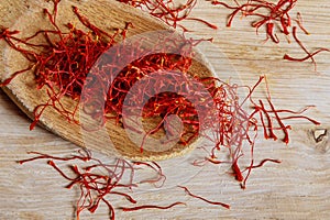 Dry saffron threads in a wooden spoon on a wooden background. photo
