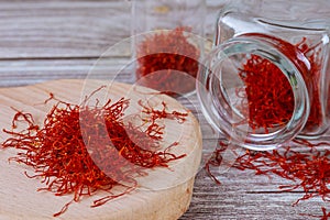 Dry saffron on a wooden board in a glass bottle. Red stamens of saffron sativus