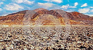 Dry salt flat crust surface, barren rugged red colorful mountains background, surreal beautiful landscape - Salar de Atacama,