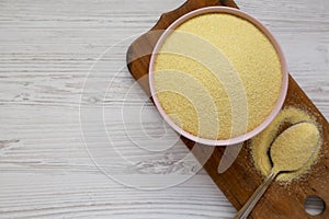 Dry semolina durum flour in a pink bowl over white wooden background, top view. Overhead, from above, flat lay. Copy space