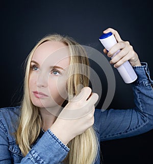 Dry shampoo. Blonde girl sprays shampoo on her hair. The problem of oily hair while traveling. An emergency remedy for excessive
