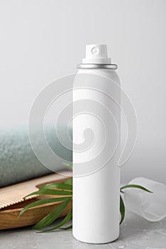 Dry shampoo spray, green twig and towel on light grey marble table