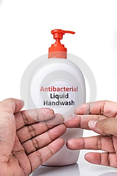 Dry skin on finger with bottle of antibacterial liquid handwash. Frequent hand washing causes skin dryness