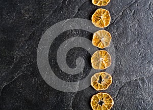 Dry slices of citrus fruits on a black slate background.