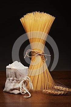 Dry spaghetti pasta, burlap bag of flour and wheat ears