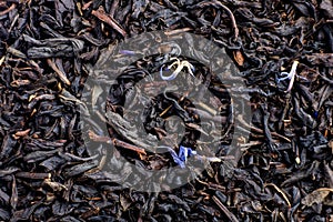 Dry tea with fruit and flower petals as background