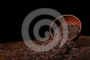 Dry tea leaves in clay bowl on black background. selective focus