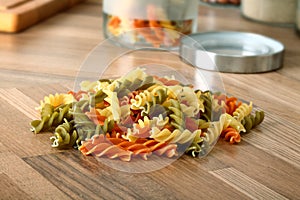 Dry tricolor rotini pasta on wooden kitchen desk photo