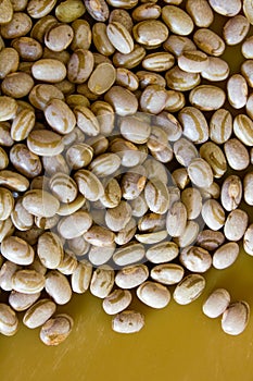 Dry and uncooked brown beans with a warm and yellow background