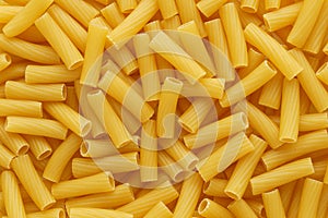 Dry uncooked tortiglioni or rigatoni pasta as a background