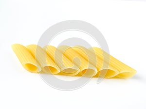 Dry uncooked yellow Italian penne pasta arranged neatly isolated on a white background.