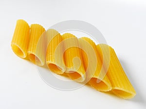Dry uncooked yellow Italian penne pasta arranged neatly isolated on a white background.