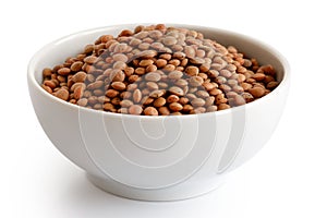 Dry unpeeled red lentils in white ceramic bowl isolated on white photo