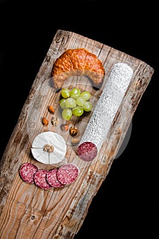 Dry variety of meat and sausages on a black plate and background