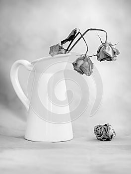 Dry wilted rose flowers on a white vase and vintage background