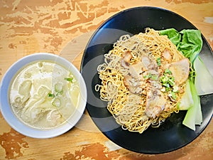 Dry wonton noodles with a bowl of soup aside. photo