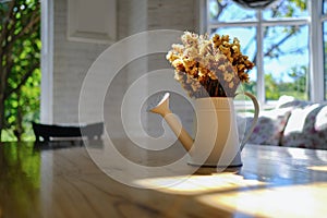 Dry yellow flower bouquet in the metal vase on wood table in the