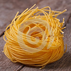 Dry yellow pasta nest close up on an old wooden