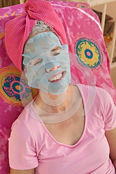 Drying beauty facial mask on smiling woman with graying hair.